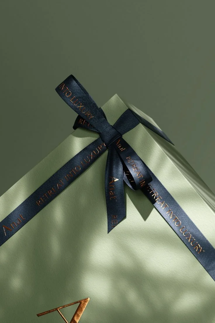 Empaque de regalo en verde con listón impreso a la marca y sello en cobre